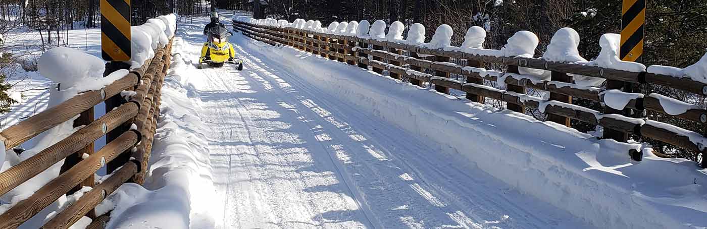 an individual snowmobiling down a snowy trail